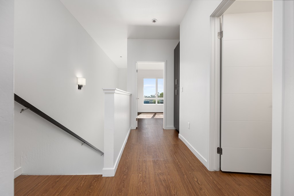 A long hallway with a wooden floor and white walls.